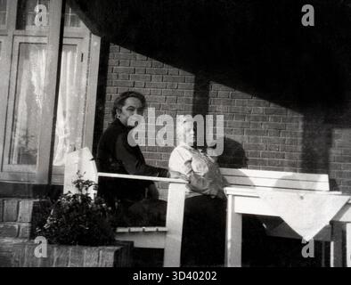 Questa fotografia, scattata intorno al 1928, mostra due persone che si godono il sole su una terrazza coperta. L'immagine proviene probabilmente da Breda, Paesi Bassi, e fa parte della collezione "Atelier Anton Henning", nota per la fotografia di ritratti. Foto Stock