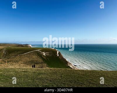 Un tranquillo paesaggio costiero alle Seven Sisters Cliffs caratterizzato da pendii verdi e orizzonte blu del mare. Foto Stock