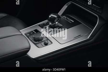 Selettore del cambio automatico e manopole della modalità di guida in auto di lusso. Interni auto scuri con finiture in metallo, primo piano della console centrale con selettore del cambio. Foto Stock