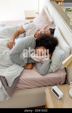 Camera moderna con sveglia digitale e lampada, in grado di ospitare due uomini che si spogliano sul letto Foto Stock