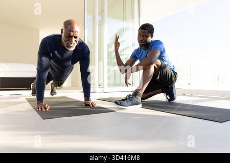Allenatori afroamericani e clienti che si allenano in palestra con materassini Foto Stock
