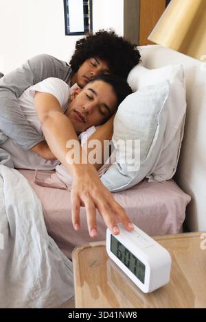 In grado di ospitare due uomini che si spogliano sul letto in una comoda camera da letto, dotata di sveglia digitale e cuscini Foto Stock