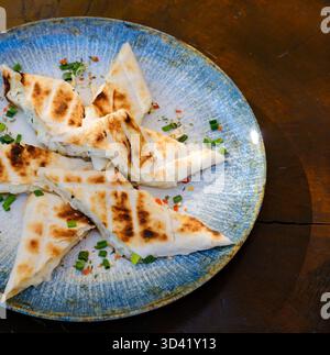 Primo piano di panini triangolari grigliati con formaggio e salsiccia su un piatto con vista sul tavolo. Foto di alta qualità Foto Stock