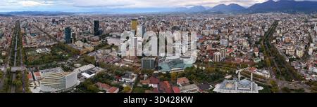 Vista aerea panoramica di Tirana, Albania, che mostra Piazza Skanderbeg, il fiume Lana e lo skyline della città incorniciato dai monti Dajti in autunno. Foto Stock
