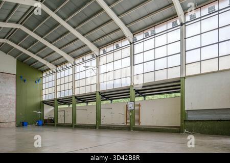 Palazzetto sportivo al coperto con ampie finestre a griglia, struttura in metallo soppalco, soffitto a volta alto, luce naturale, palestra vuota, struttura polivalente Foto Stock