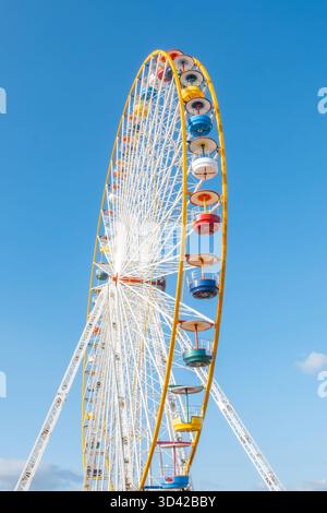 Vista ad angolo basso di una grande e colorata struttura della ruota panoramica su un cielo blu profondo e limpido in una giornata di sole Foto Stock