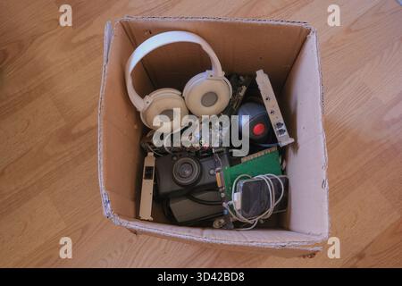 Rifiuti elettronici. Vecchi accessori elettronici imbottiti in una scatola di cartone. Dispositivi tecnologici scartati. Concetto di rifiuti elettronici. Foto Stock
