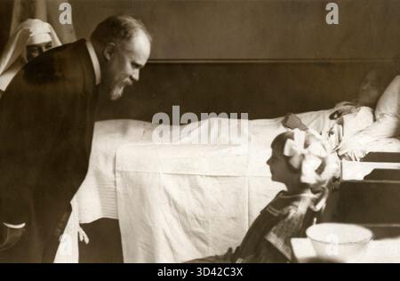 Raymond Poincaré, lo statista francese che ha prestato servizio come presidente dal 1913 al 1920, è visto qui parlare con la giovane paziente Elizabeth Camerun durante una visita in un ospedale francese a Londra, nel 1913. Foto Stock