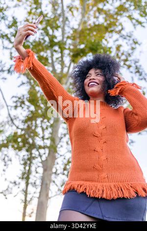 Giovane donna nera sorridente che si diverte con un selfie all'aperto con il suo cellulare Foto Stock