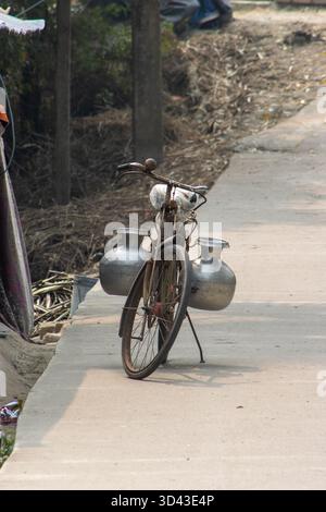 Tradizionale bicicletta locale con container per miglia parcheggiati sulla strada e isolati su uno sfondo naturale nei Sundarbans vicino a Kolkata, in India Foto Stock