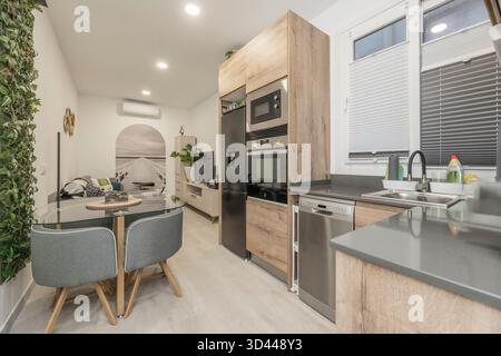 Vista di una cucina con un sistema di porte scorrevoli per separare visivamente lo spazio quando necessario, con mobili bianchi e un ripiano in legno Foto Stock