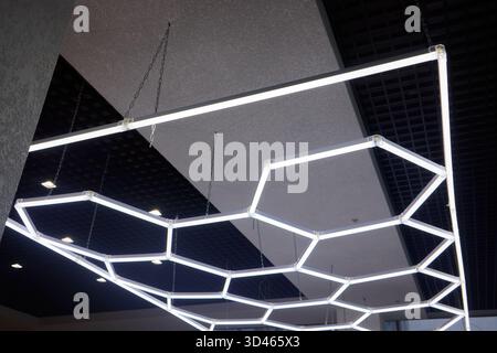Eleganti apparecchi esagonali che migliorano gli ambienti di ufficio e di vendita al dettaglio moderni, innovativa illuminazione a soffitto con forme geometriche per elevare il livello commerciale Foto Stock