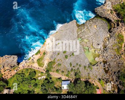 Potenti onde oceaniche che si infrangono contro aspre scogliere calcaree sull'isola di Nusa Penida, Bali Foto Stock