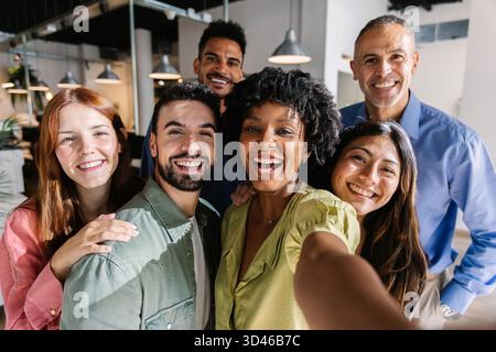 Gruppi diversi di colleghi di lavoro che scattano selfie in ufficio Foto Stock
