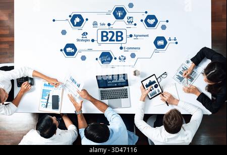 Una visione dall'alto verso il basso dei professionisti che collaborano alle strategie B2B utilizzando strumenti digitali. Lo spazio di lavoro moderno include notebook, tablet e. Foto Stock