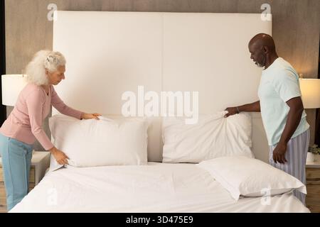Cuscini per lisciare diverse coppie di biancheria bianca nella camera da letto moderna, con letto king size Foto Stock