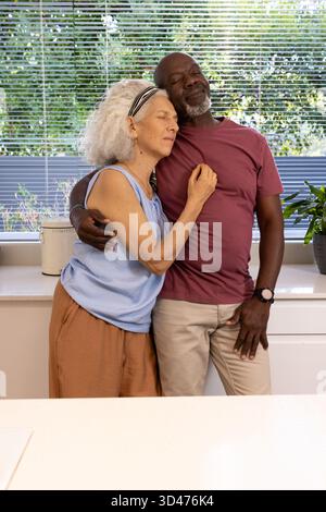 Diverse coppie senior che abbracciano una cucina moderna, con canister di compost e piante in vaso Foto Stock