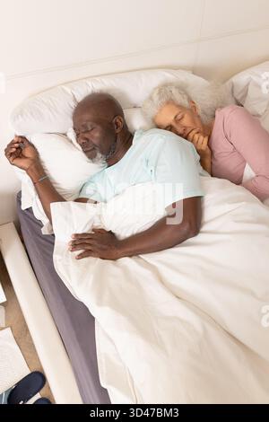 Diverse coppie di anziani che dormono fianco a fianco in camera da letto, con piumone e cuscini bianchi Foto Stock