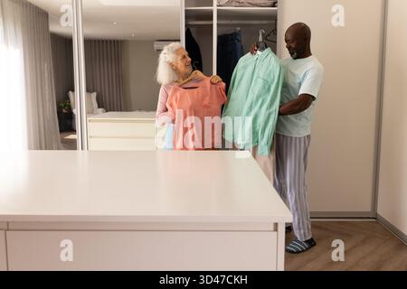 In piedi diverse coppie che reggono camicie su grucce di legno nell'armadio a muro, con comò dell'isola Foto Stock