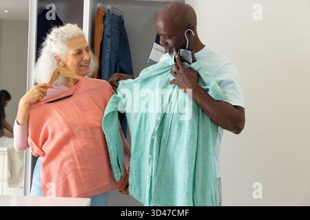 Confrontando gli abiti di diverse coppie senior che indossano le camicie nell'armadio, con le camicie in corallo e menta Foto Stock