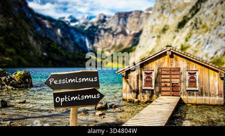 Un'immagine con un cartello che punta in due direzioni diverse in tedesco. Una direzione punta all'ottimismo, l'altra al pessimismo. Foto Stock
