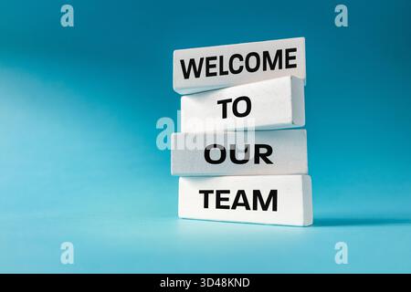 Benvenuto nel nostro team. Concetto di business. Collaboratore prezioso, lavoro di squadra, approccio individuale. Motivazione nell'organizzazione. Slogan scritto su legno bianco Foto Stock