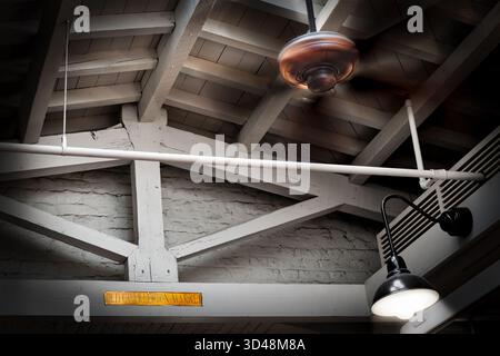 Un ventilatore a soffitto gira lentamente, muovendo aria , all'interno della cornice in mattoni e legno dell'Old Charleston Market a Charleson, Carolina del Sud. Foto Stock