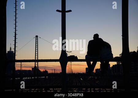 Bella coppia seduta sul ponte durante il tramonto Foto Stock
