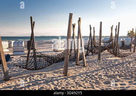 Spiaggia del Mar Baltico con strutture amaca in legno e sedie in vimini in calda luce serale. Tranquillo scenario balneare, relax, viaggi e vacanze estive Foto Stock