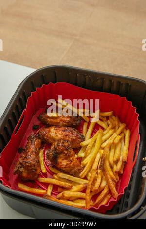 La disposizione verticale degli spiedini di pollo croccanti in cima alle patatine crea un'altezza visiva, mentre i filamenti di salsa teriyaki collegano tutti gli elementi del d Foto Stock