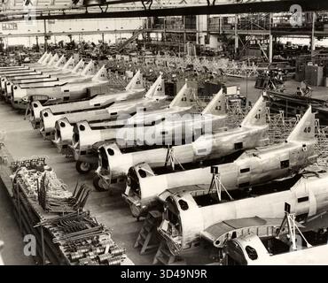 Questa fotografia mostra la sala riunioni della fabbrica della North American Aviation (NAA) a Inglewood, California, scattata nel 1939. La NAA era un importante produttore di aerei statunitense, fondata dal finanziere Clement Melville Keys nel 1928. La compagnia produsse aerei notevoli sia per uso civile che militare, tra cui il famoso caccia P-51 Mustang della seconda guerra mondiale. Lo stabilimento di Inglewood fu centrale per la produzione di aeromobili negli anni pre-bellici e bellici, mostrando la tecnologia dell'aviazione industriale all'inizio del XX secolo, la produzione di linee di assemblaggio e l'espansione dell'industria aerospaziale statunitense. Foto Stock
