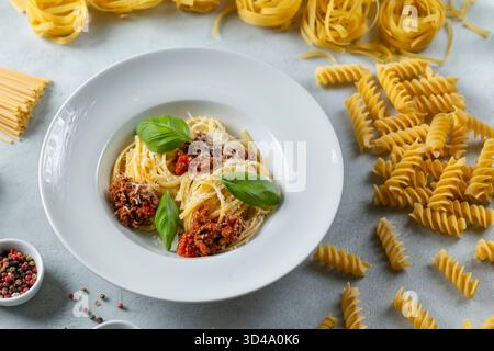 Deliziosi spaghetti alla bolognese preparati con basilico fresco e parmigiano grattugiato Foto Stock