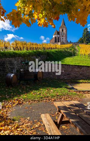 Pittoresco paesaggio autunnale caratterizzato da una chiesa storica su una collina che si affaccia sui vigneti e da un tradizionale frantoio Foto Stock
