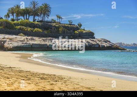 Una vista di Playa del Duque, dove le sabbie dorate si estendono verso acque cristalline e turchesi. Le dolci onde e il verde avvolgono questa spiaggia di Tenerife, provi Foto Stock