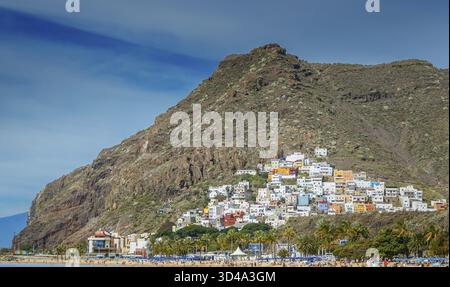 Una vista pittoresca del villaggio di San Andres a Tenerife, annidato alla base di un'aspra montagna. Case colorate sono raggruppate sul fianco della collina, con una Foto Stock