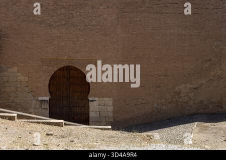 Moresco arco islamico al di sopra di una porta di legno in Granada, Spagna, Europa in una luminosa giornata di sole Foto Stock