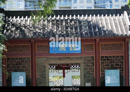 Chinese Garden of Friendship, Sydney. Cancello d'ingresso cinese tradizionale con tetto di piastrelle scure, reticolo ornato e cartello blu con il cinese dorato Foto Stock
