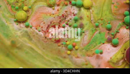 Bolla art. Acqua d'inchiostro. Verde sfocato giallo rosso colorato olio rotondo glitter flusso acrilico fluttuante su sfondo astratto. Foto Stock