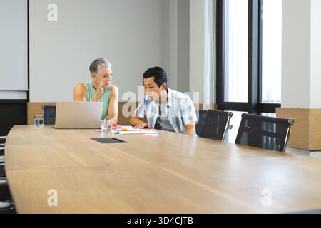 Indicare i vari colleghi che si appoggiano sui documenti della sala conferenze, con laptop e pennarelli Foto Stock