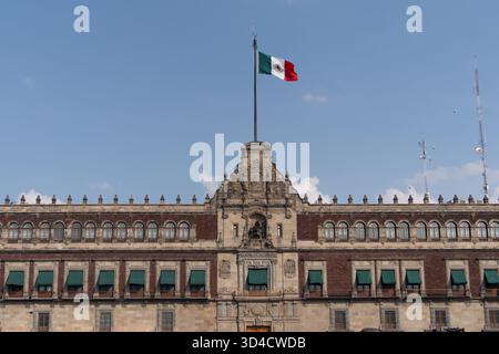 Un grande edificio con una bandiera sopra di esso. La bandiera è rossa, bianca e verde. La tradizione messicana del giorno dei morti, offerte, cibo, colori, decorazioni, Foto Stock