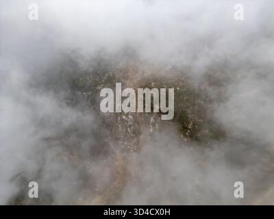 Vista su una tortuosa strada di montagna che attraversa la nebbia Foto Stock