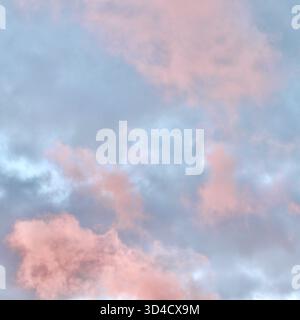 Un'atmosfera da sogno in cui una massa drammatica di nuvole di rosa e pesca si illumina contro una malva pallida e il cielo blu durante il tramonto o l'alba, riempiendosi Foto Stock