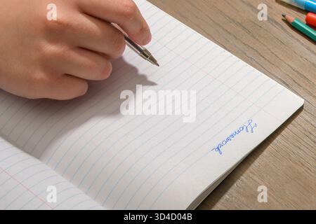 Primo piano della mano di un adolescente che inizia a fare i compiti. Penna in mano e notebook Foto Stock