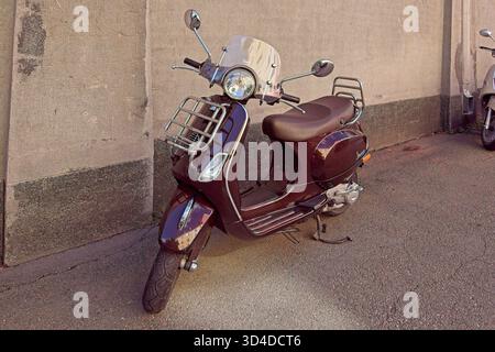 Vallila, Helsinki, Finlandia - 13 agosto. 2025: Vespa LX parcheggiata sul marciapiede davanti al muro. Foto Stock