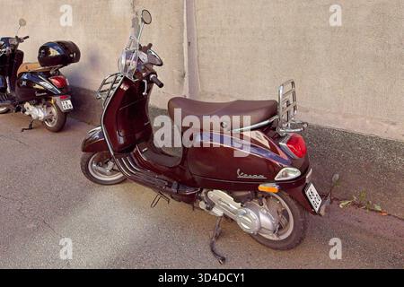 Vallila, Helsinki, Finlandia - 13 agosto. 2025: Vespa LX parcheggiata sul marciapiede davanti al muro. Foto Stock