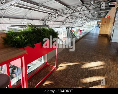 Nowy Dwor Mazowiecki, Polonia - 22 ottobre 2025: Interni moderni all'aeroporto con soffitto a lucernario, vegetazione e un corridoio spazioso. Foto Stock