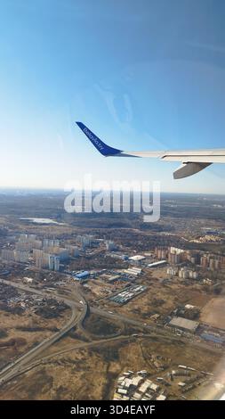 Vista aerea dalla finestra dell'aeroplano che mostra l'ala Aeroflot sul paesaggio urbano durante l'avvicinamento a Mosca, Russia. Periferia invernale della città Foto Stock