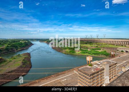 Un'ampia vista della massiccia diga di Itaipu e della sua centrale idroelettrica, mostrando il muro della diga e l'edificio amministrativo. Foto Stock