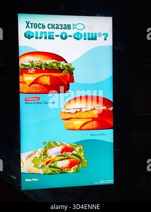 Kiev, Ucraina - 10 novembre 2025: Cartello fast food di Bright McDonald's che mostra hamburger di pesce, involtini e verdure fresche su sfondo blu. Foto Stock