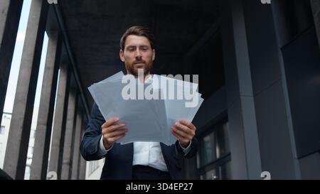 Uomo d'affari caucasico maturo di successo con documenti in mano in città occupato con un contratto di lavoro dirigente d'affari di mezza età Foto Stock